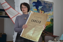 Сотрудник музея Н. В. Поздеева демонстрирует «Атлас реки Енисея» подполковника Вилькицкого.